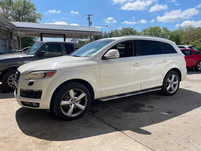 White first-generation Audi Q7 parked outside the shop