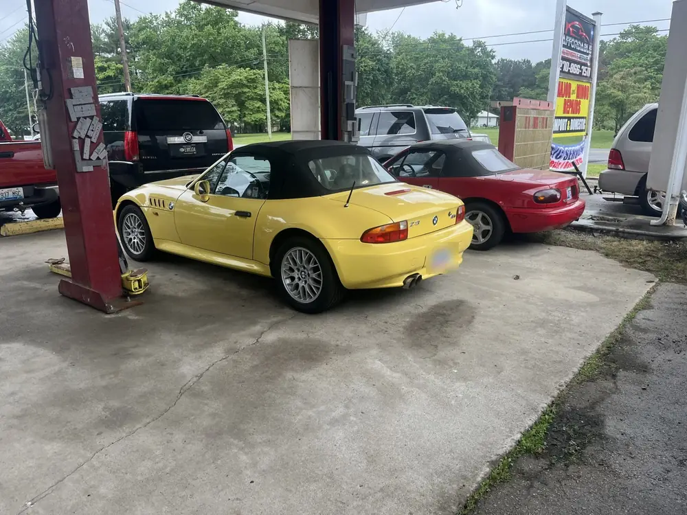 Yellow BMW Z3 roadster under the shop canopy