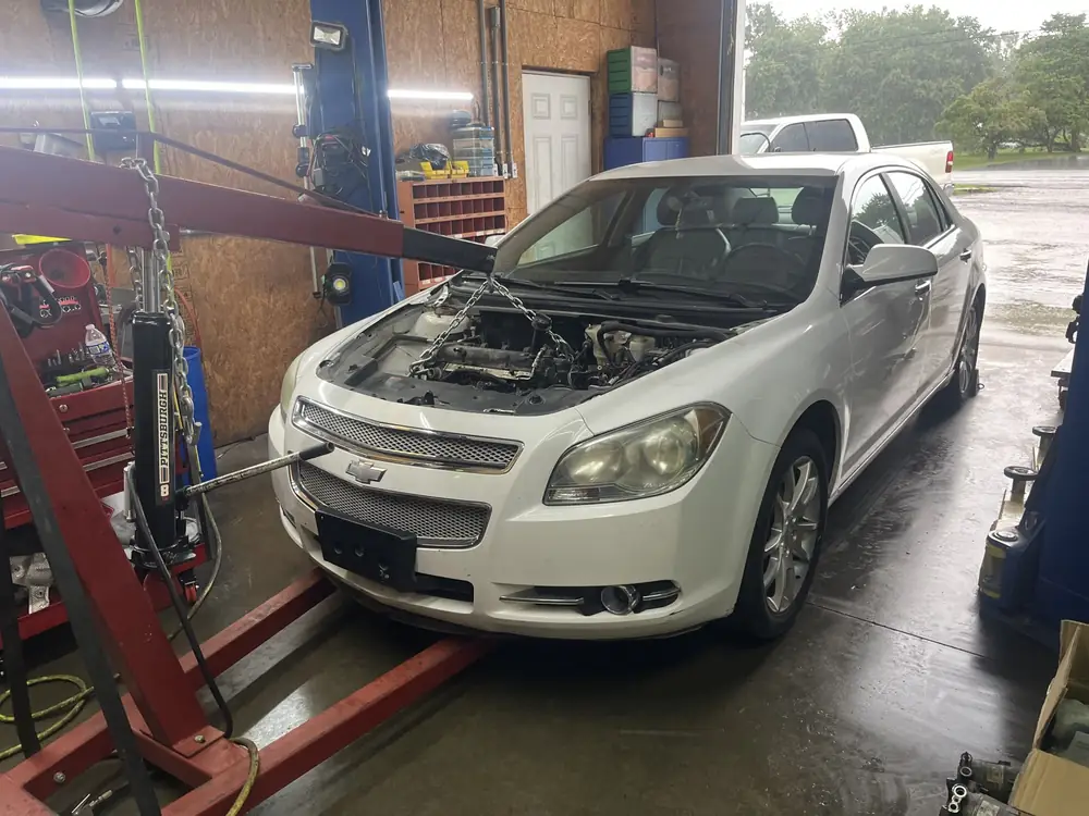 White Chevrolet Malibu on the lift with the hood open